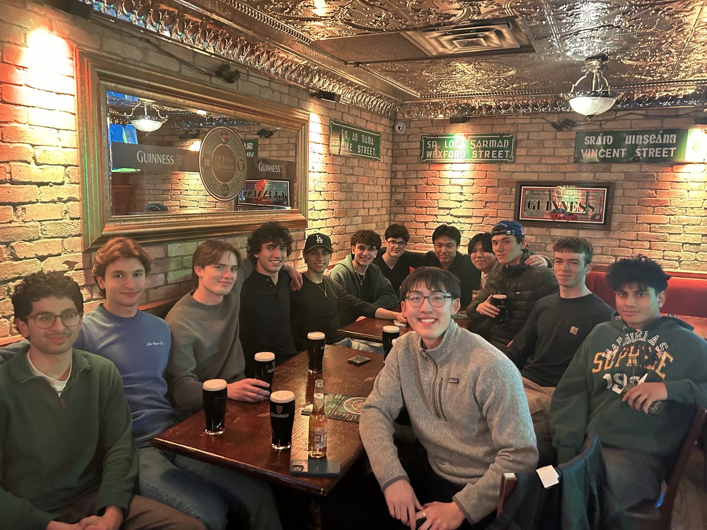 A long table of friends with pints in a wood-panelled pub.
