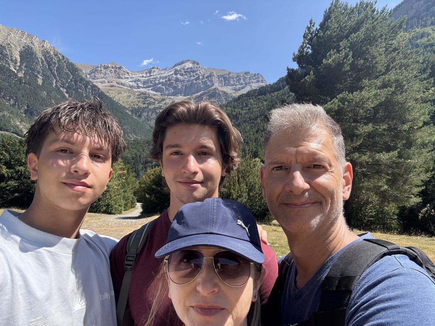 A family selfie on a mountain trail, with a limestone ridge in the background.
