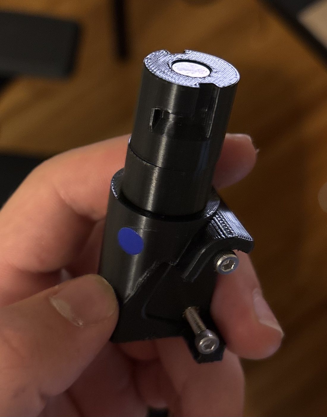 3D-printed cylindrical hand mount held in hand, showing a magnet at the top, a keyed slot for the turn-to-lock, and mounting screws.