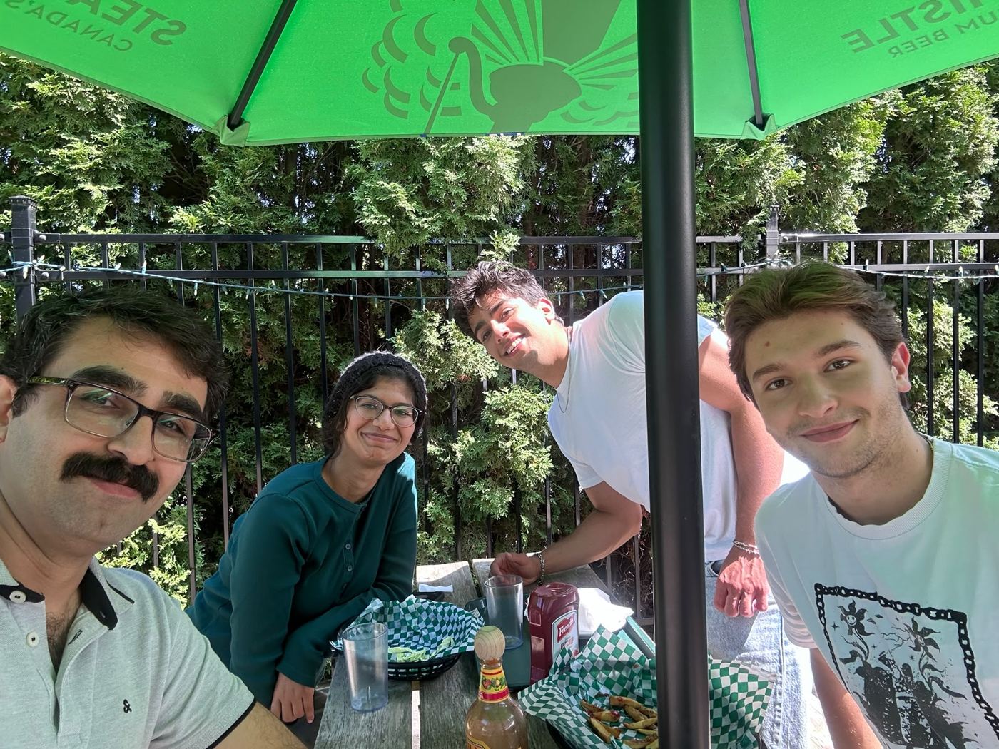 Marc Masgoret and three labmates from the Mirzaei research group sitting together at an outdoor table.